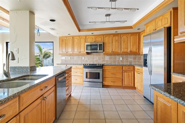 kitchen featuring dark stone countertops, a raised ceiling, sink, appliances with stainless steel finishes, and light tile patterned floors