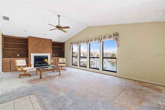 unfurnished living room featuring ceiling fan, lofted ceiling, a fireplace, a water view, and built in shelves