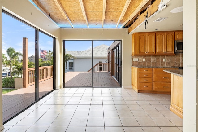 kitchen featuring decorative backsplash, light tile patterned floors, and dark stone countertops