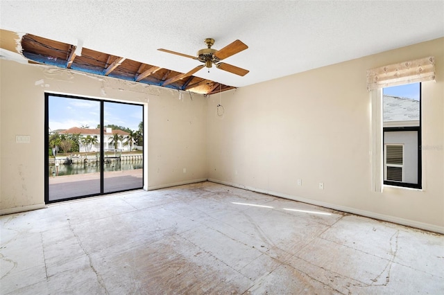 unfurnished room with ceiling fan, a healthy amount of sunlight, and a water view