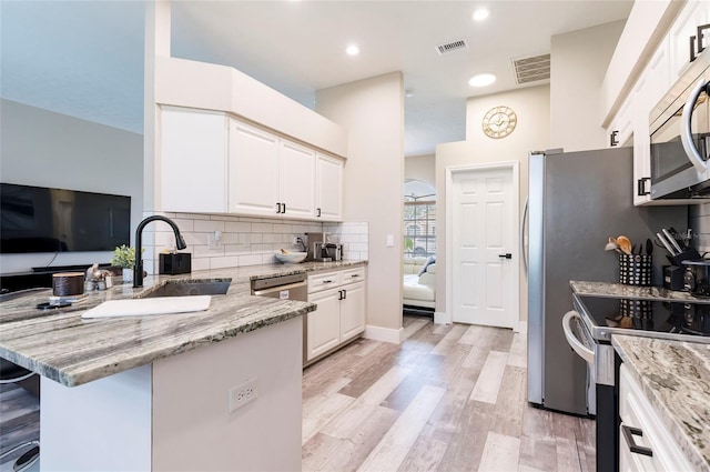 kitchen featuring sink, stainless steel appliances, kitchen peninsula, and white cabinets