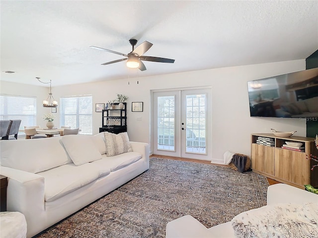 living room with french doors, ceiling fan with notable chandelier, and a textured ceiling