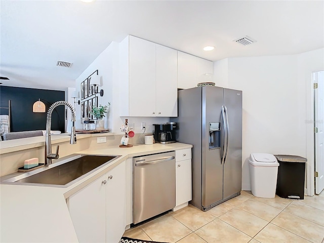 kitchen with appliances with stainless steel finishes, sink, light tile patterned floors, and white cabinets