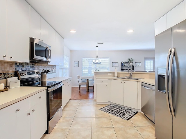 kitchen featuring sink, white cabinetry, tasteful backsplash, hanging light fixtures, and stainless steel appliances