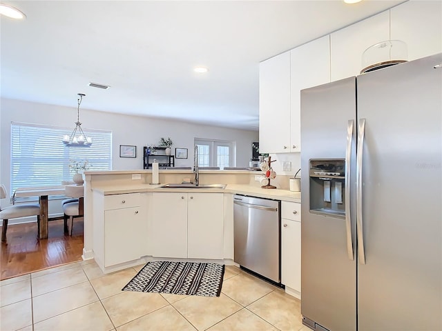 kitchen with white cabinetry, appliances with stainless steel finishes, kitchen peninsula, and hanging light fixtures