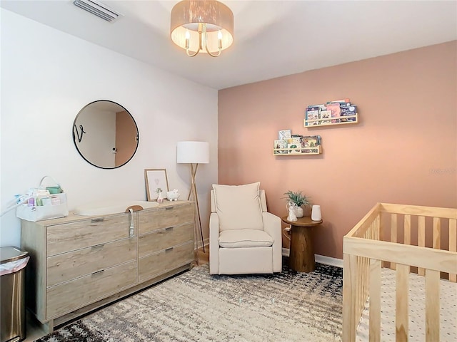 carpeted bedroom with a nursery area and a notable chandelier