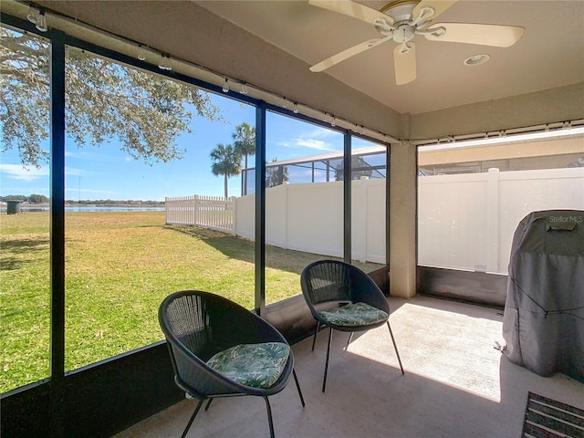 sunroom with a water view and ceiling fan