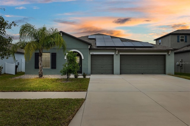 view of front of house with a garage, a lawn, and solar panels