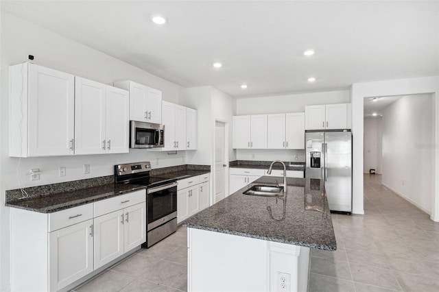 kitchen featuring dark stone countertops, sink, white cabinets, an island with sink, and stainless steel appliances