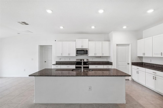 kitchen featuring a center island with sink, dark stone countertops, and stainless steel appliances