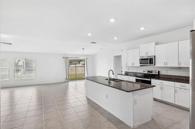 kitchen with dark stone countertops, sink, white cabinets, an island with sink, and stainless steel appliances