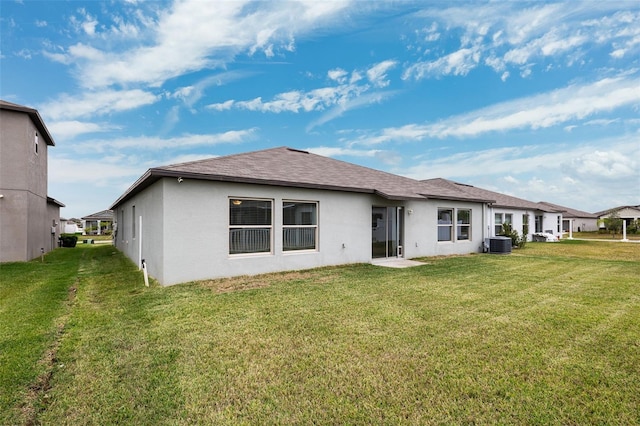 rear view of property with central AC unit and a lawn