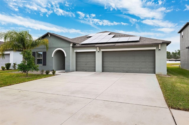 single story home featuring solar panels, a front yard, and a garage