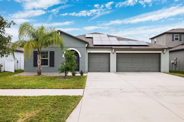 view of front of property featuring a garage, a front lawn, and solar panels