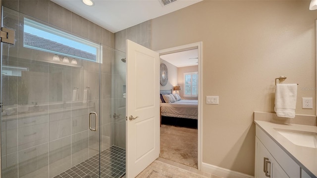 bathroom featuring a shower with shower door, a healthy amount of sunlight, tile patterned floors, and vanity