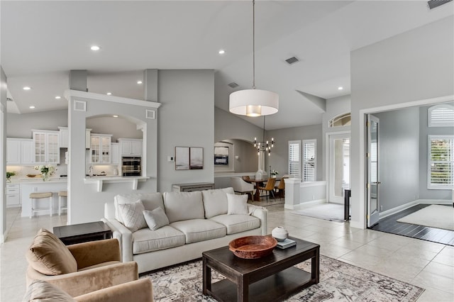 living room featuring high vaulted ceiling, plenty of natural light, light tile patterned floors, and a notable chandelier