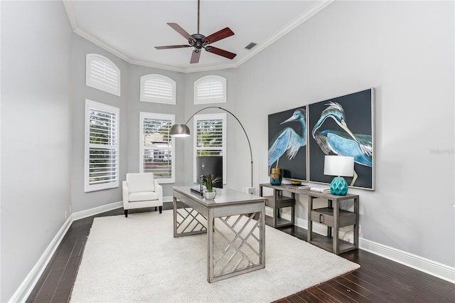 home office with dark wood-type flooring, a towering ceiling, ceiling fan, and ornamental molding