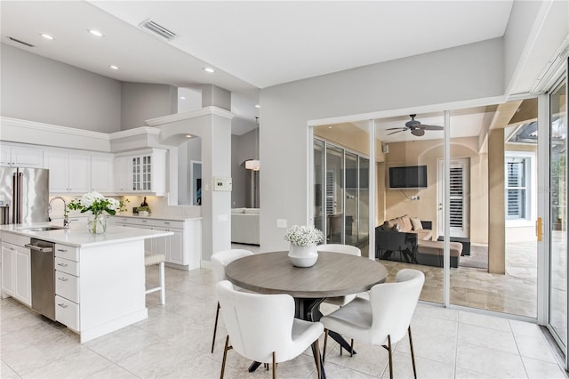 dining space with sink, ceiling fan, and a towering ceiling