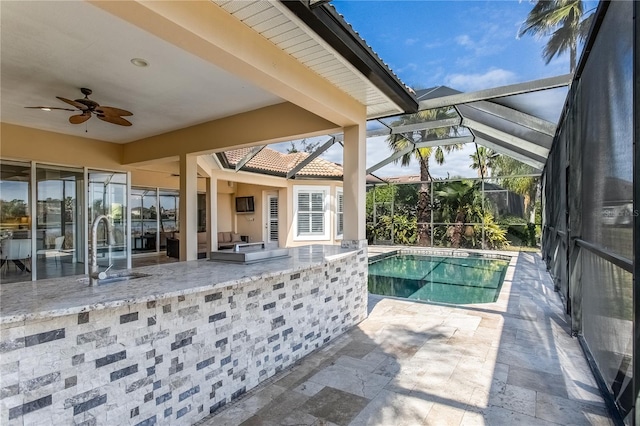 view of swimming pool featuring an outdoor kitchen, a patio, ceiling fan, a lanai, and an outdoor wet bar