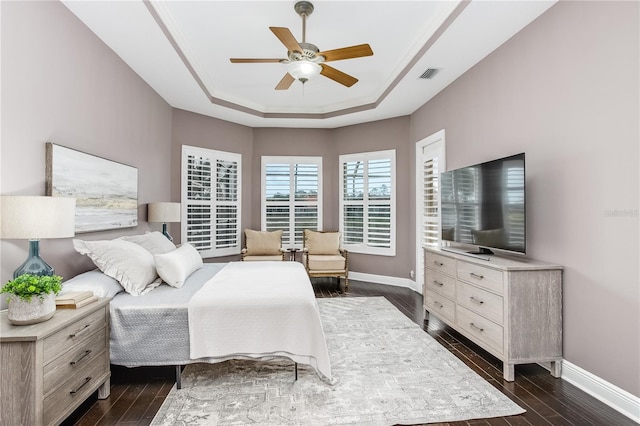 bedroom with ceiling fan, dark wood-type flooring, ornamental molding, and a raised ceiling