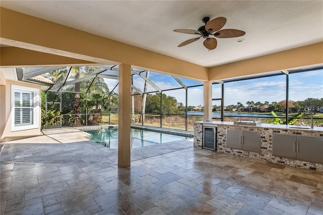 view of pool with exterior kitchen, a patio area, sink, ceiling fan, and a lanai