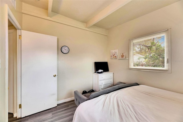 bedroom with dark hardwood / wood-style flooring and beamed ceiling