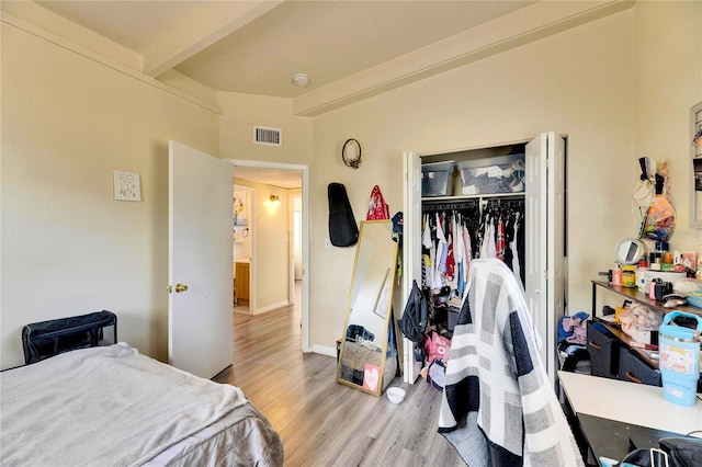 bedroom featuring light hardwood / wood-style floors, a closet, and beam ceiling