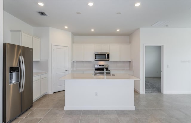 kitchen featuring a center island with sink, visible vents, stainless steel appliances, light countertops, and a sink