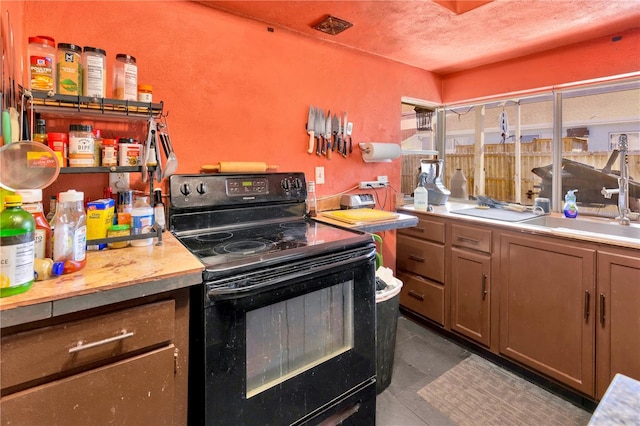 kitchen featuring black electric range, dark tile patterned flooring, and sink