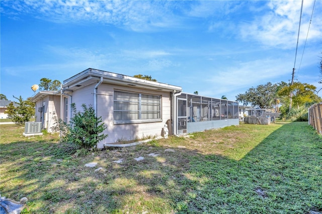 view of property exterior featuring central AC unit, a yard, and a sunroom