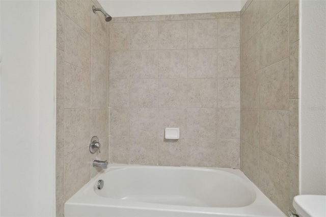 bathroom featuring tiled shower / bath combo and toilet