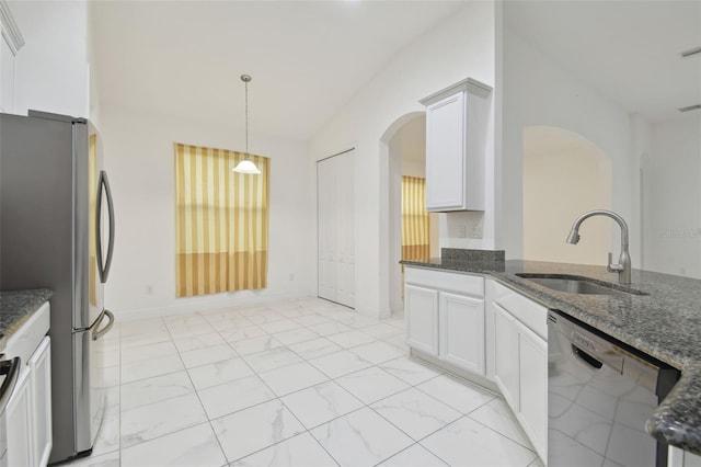 kitchen featuring appliances with stainless steel finishes, sink, white cabinets, dark stone counters, and hanging light fixtures