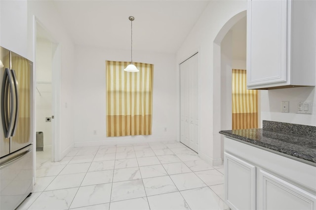 kitchen featuring pendant lighting, white cabinets, stainless steel refrigerator, and dark stone counters