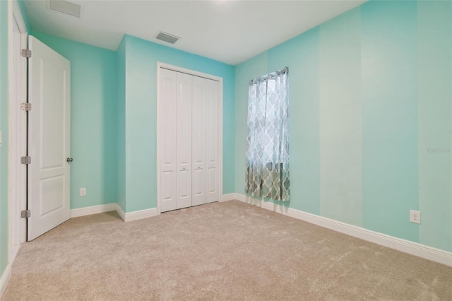 unfurnished bedroom with light carpet and a closet