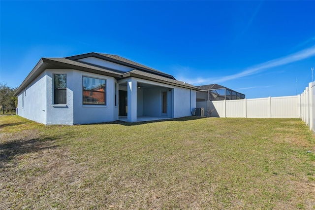 back of property featuring a lanai and a lawn