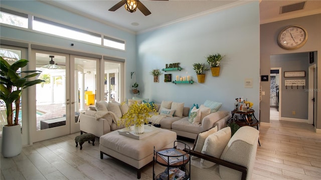 living room featuring a high ceiling, crown molding, light hardwood / wood-style floors, and french doors