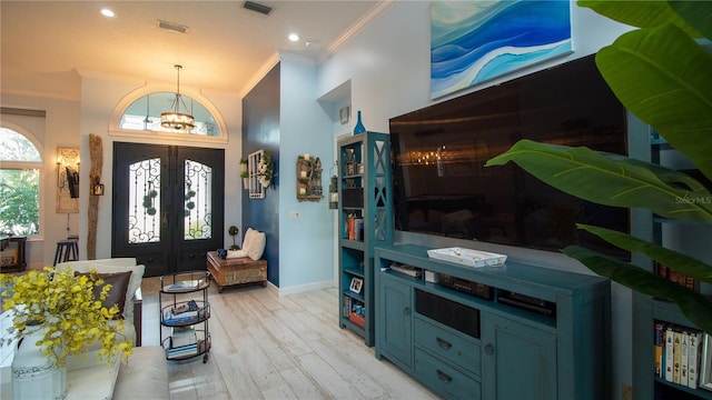 entrance foyer featuring crown molding, a chandelier, light hardwood / wood-style floors, and french doors