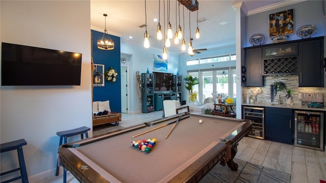 playroom featuring ornamental molding, bar area, beverage cooler, and light hardwood / wood-style floors