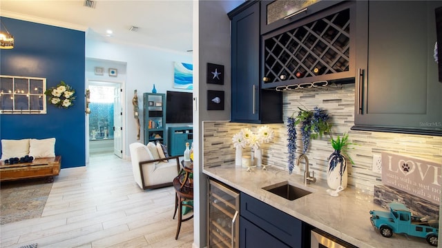 bar featuring sink, light hardwood / wood-style flooring, ornamental molding, beverage cooler, and decorative backsplash