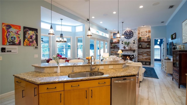 kitchen with sink, decorative light fixtures, stainless steel dishwasher, plenty of natural light, and a large fireplace