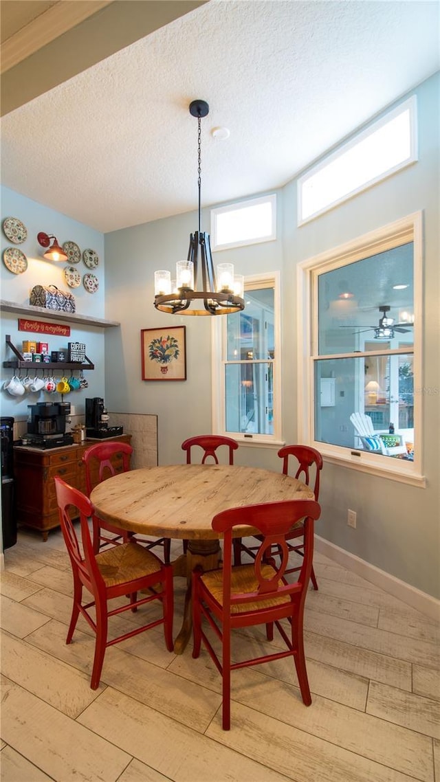 dining area featuring a chandelier, a textured ceiling, and light wood-type flooring