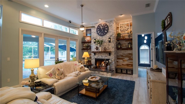 living room featuring crown molding, a fireplace, a high ceiling, and light wood-type flooring