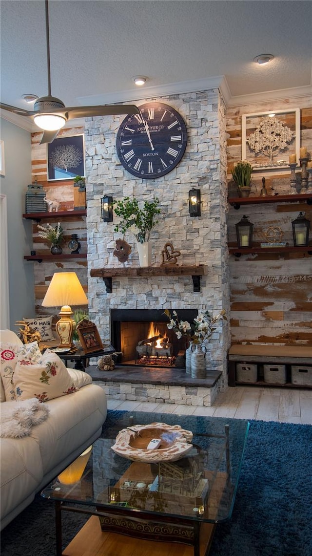 living room featuring ornamental molding, a fireplace, light hardwood / wood-style floors, and a textured ceiling