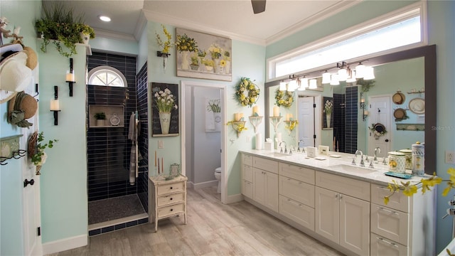 bathroom featuring tiled shower, ornamental molding, toilet, and vanity