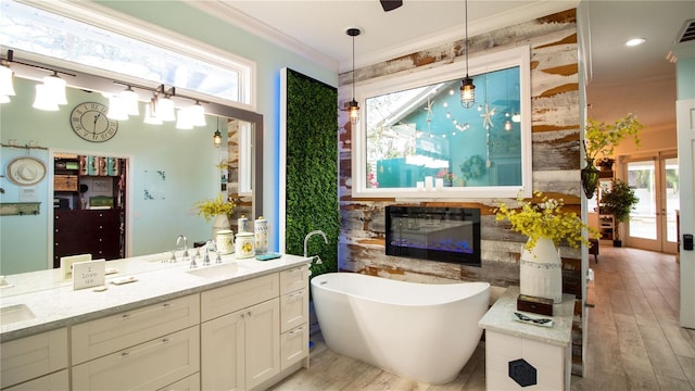 bathroom with crown molding, plenty of natural light, vanity, and a tub to relax in