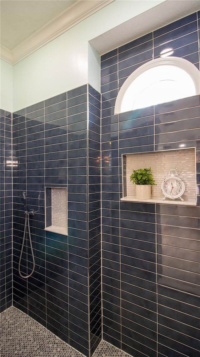 bathroom featuring ornamental molding and tiled shower