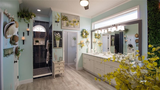 bathroom featuring vanity, ornamental molding, toilet, and tiled shower