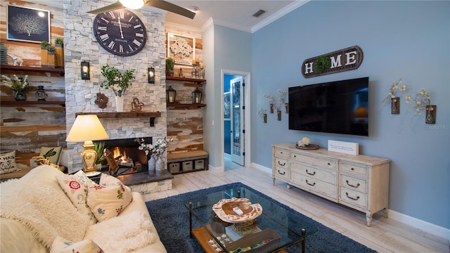 living room with a stone fireplace, ornamental molding, light hardwood / wood-style floors, and ceiling fan