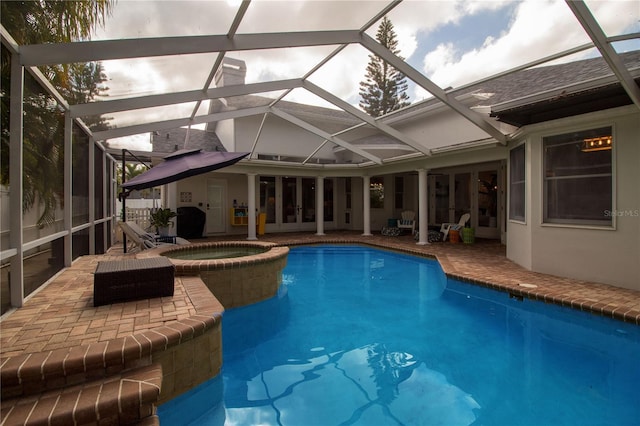 view of swimming pool featuring a patio area, glass enclosure, and an in ground hot tub