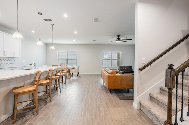 kitchen featuring sink, a breakfast bar area, white cabinets, pendant lighting, and backsplash